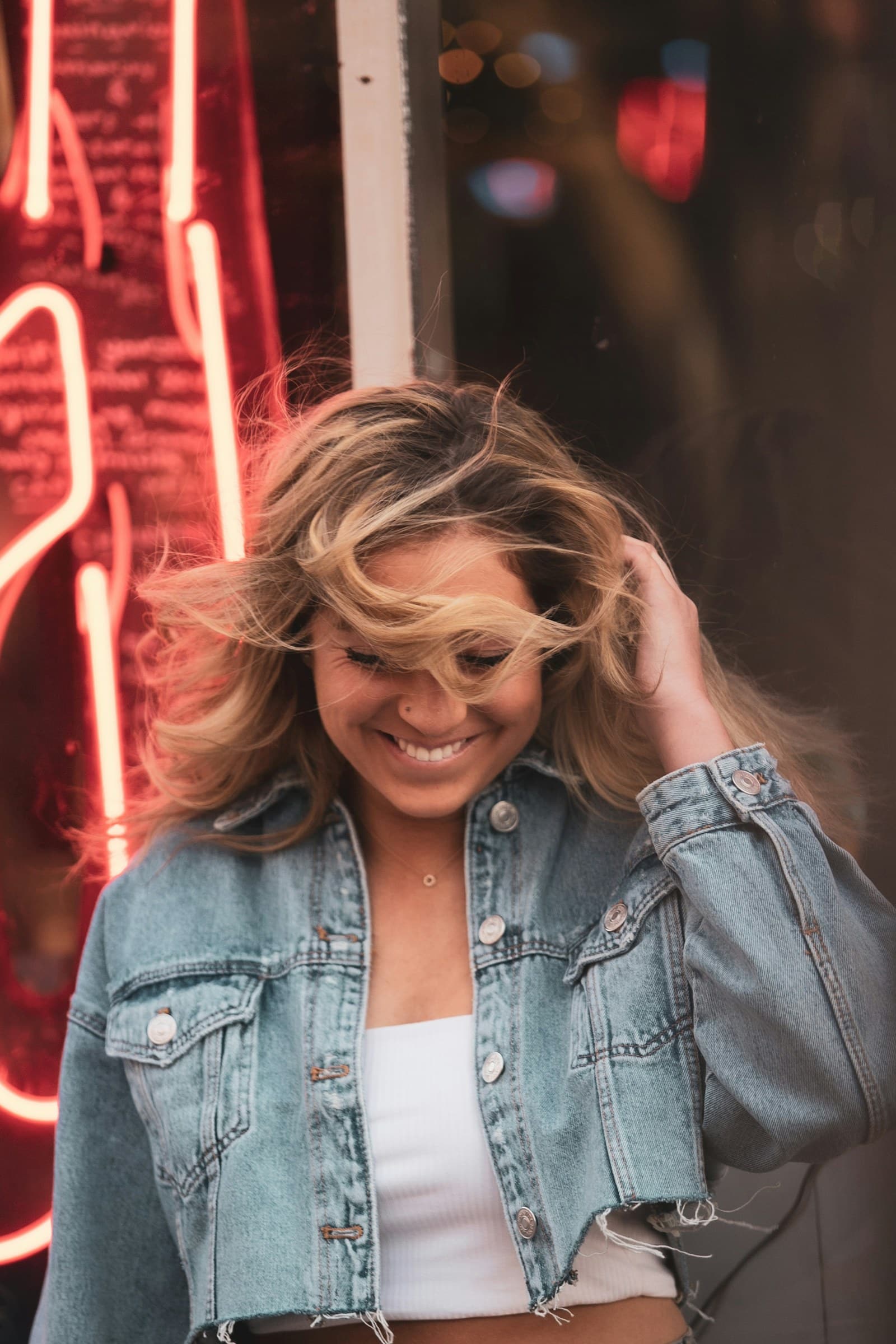 Platzhalterfoto: lächelnde Person in Jeansjacke vor einem Neonschild