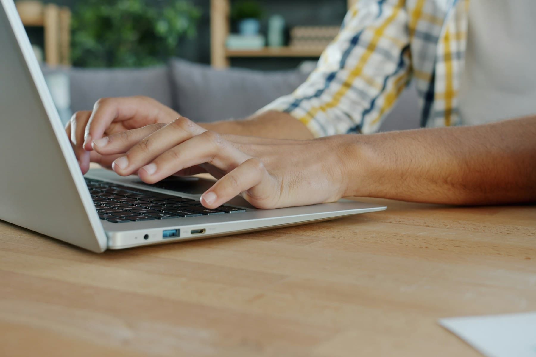 Platzhalterfoto: Hände tippen auf einem Laptop an einem Holztisch